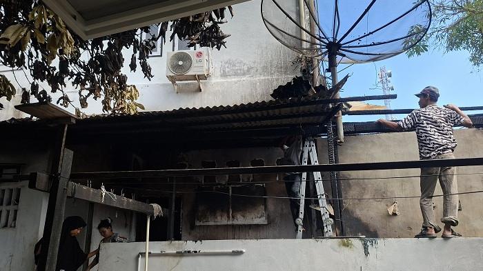 Para warga membersihkan puing-puing dan isi bangunan tempat usaha laundry yang terbakar di Jalan Iskandar Muda Gampong Ujong Kalak, Kecamatan Johan Pahlawan, Aceh Barat, Selasa (28/10/2025).