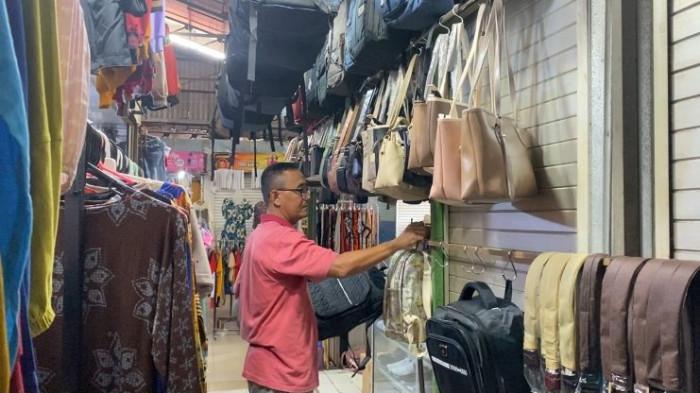 MENATA DAGANGAN - Pranata, pedagang tas dan sepatu di Pasar Segamas Purbalingga memajang dagangannya, Kamis (2/10/2025). Pedagang tas dan sepatu di Pasar Segamas Purbalingga mengeluhkan sepi pembeli sejak marak penjualan daring.