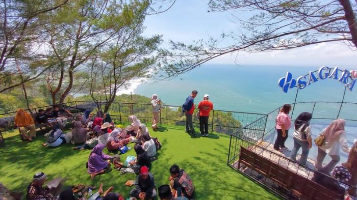 PIKNIK - Pengunjung bersantai duduk lesehan di bukit Sagara View Karangbolong dengan pemandangan lepas pantai di wilayah Kecamatan Buayan, Kabupaten Kebumen, Jawa Tengah, Minggu (14/9/2025).