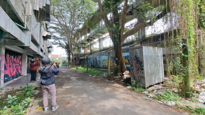 KEBONDALEM PURWOKERTO - Seorang warga saat memotret bangunan mangkrak di kawasan komplek kawasan Kebondalem, Purwokerto, Kabupaten Banyumas, Selasa (4/3/2025). Aset kompleks Kebondalem resmi diserahkan kepada Pemerintah Kabupaten (Pemkab) Banyumas setelah hampir dua dekade bermasalah. Tribunbanyumas.com/Permata Putra Sejati