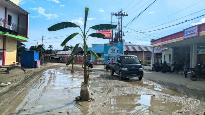 JALAN RUSAK — Dua pohon pisang berdiri di tengah jalan. Masyarakat kawasan Pasar Rakyat Hulawa menanam pohon pisang di jalan yang rusak.