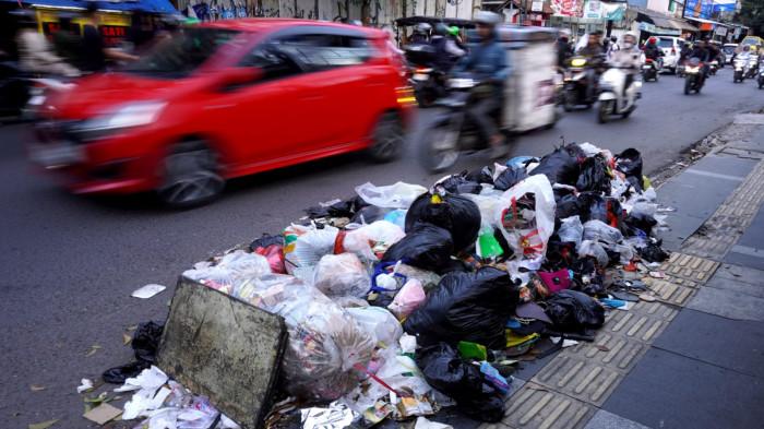 Kendaraan bermotor melintas di samping tumpukan sampah di pinggir Jalan Cibaduyut Raya, Kota Bandung, Jawa Barat, Rabu (30/7/2025).
