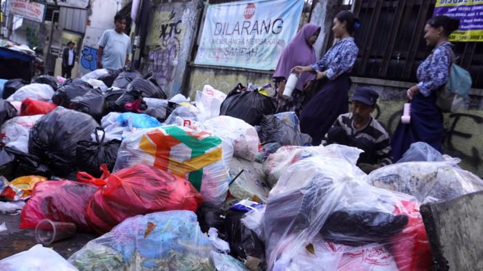 Pejalan kaki melintas di samping tumpukan sampah di pinggir Jalan Cibaduyut Raya, Kota Bandung, Jawa Barat, Rabu (30/7/2025).
