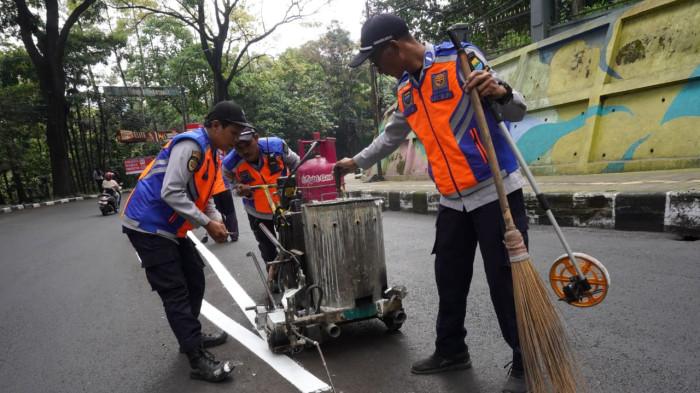Petugas Dinas Perhubungan (Dishub) Kota Bandung membuat marka jalan berupa garis utuh dengan cat warna putih di tengah permukaan Jalan Siliwangi, Kota Bandung, Jawa Barat, Kamis (21/8/2025).