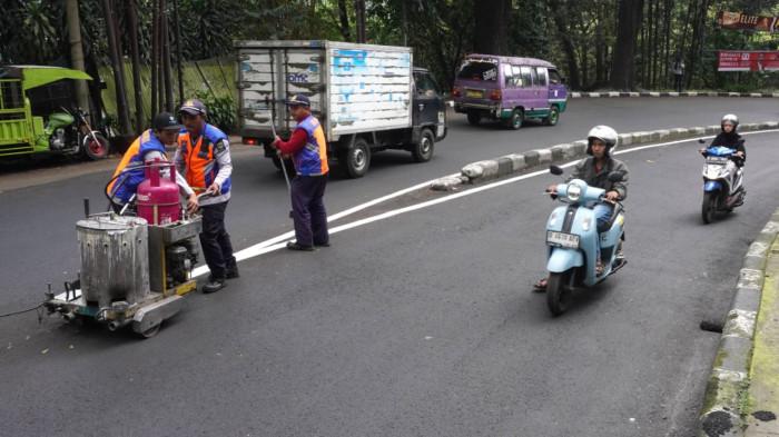 Petugas Dinas Perhubungan (Dishub) Kota Bandung membuat marka jalan berupa garis utuh dengan cat warna putih di tengah permukaan Jalan Siliwangi, Kota Bandung, Jawa Barat, Kamis (21/8/2025).