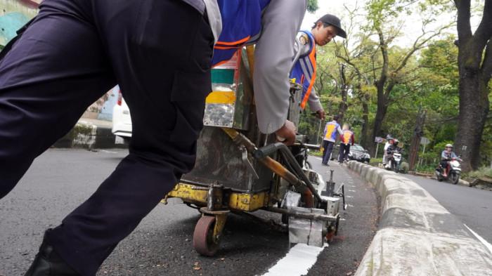 Petugas Dinas Perhubungan (Dishub) Kota Bandung membuat marka jalan berupa garis utuh dengan cat warna putih di tengah permukaan Jalan Siliwangi, Kota Bandung, Jawa Barat, Kamis (21/8/2025).