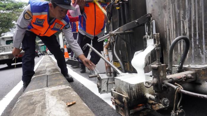 Petugas Dinas Perhubungan (Dishub) Kota Bandung membuat marka jalan berupa garis utuh dengan cat warna putih di tengah permukaan Jalan Siliwangi, Kota Bandung, Jawa Barat, Kamis (21/8/2025).
