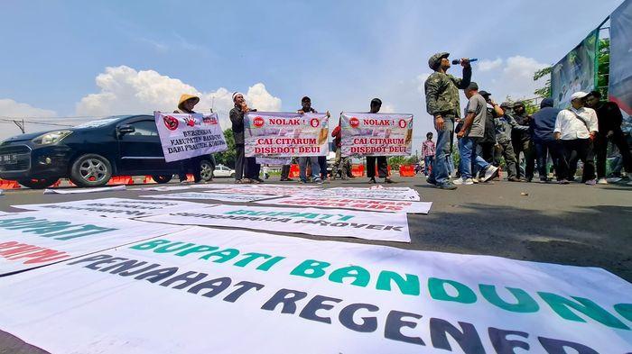 UNJUK RASA - Puluhan warga Kabupaten Bandung menggelar aksi unjuk rasa di depan gerbang Kompleks Pemerintah Kabupaten (Pemkab) Bandung, Soreang pada Kamis (9/10/2025).