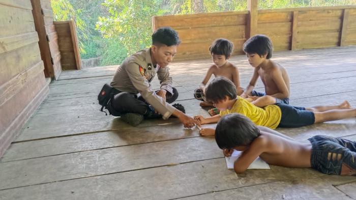 MENGEDUKASI - Perbal Tampung, Orang Rimba yang menjadi polisi di Polres Sarolangun, sedang mengedukasi anak Rimba.