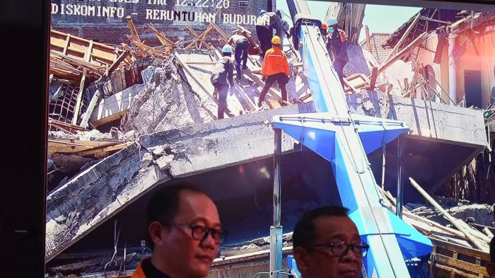 ALAT BERAT DIKERAHKAN - Tampilan live alat berat mulai dikerahkan untuk membongkar puing Musala Ponpes Al Khoziny untuk mengevakuasi korban yang terjebak puing ditayangkan di posko Basarnas, Kamis (2/10/2025).