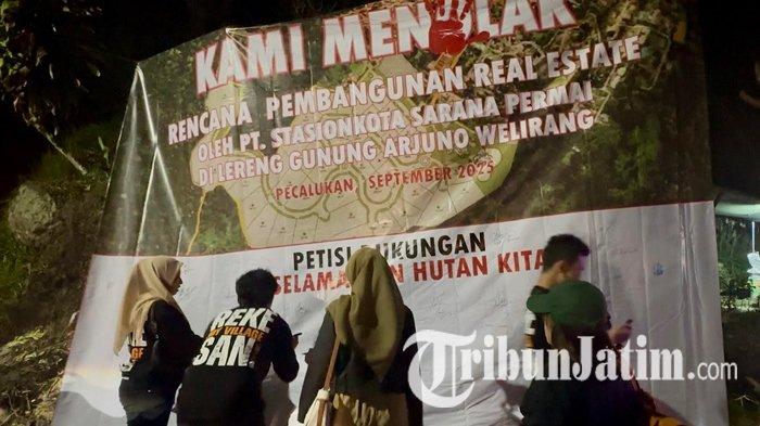 TOLAK PEMBANGUNAN - Warga dari tiga kelurahan, yakni Prigen, Pecalukan dan Ledug, Pasuruan, berkumpul di Posko Perlawanan Penolakan Real Estate di depan pintu masuk Air Terjun Kakek Bodo, Kecamatan Prigen, Pasuruan, Jawa Timur, Sabtu (25/10/2025) malam. Aksi protes pembangunan di lereng Gunung Arjuno-Welirang ini dibuktikan dengan pembubuhan tanda tangan petisi oleh masyarakat Prigen sebagai simbol perlawanan.
