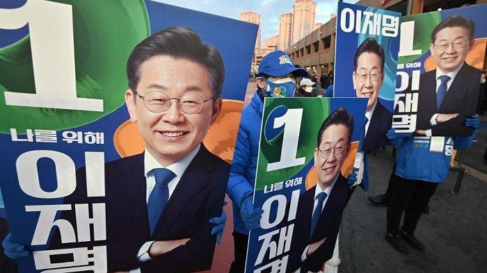 Pendukung calon presiden Korea Selatan Lee Jae-myung dari Partai Demokrat yang berkuasa memegang plakat yang menunjukkan foto-foto Lee selama kampanye pemilihan di Seoul pada 15 Februari 2022.