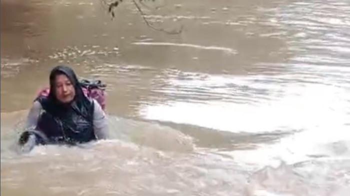 AKSI NEKAT BIDAN: Aksi nekat bidan Dona terekam saat menyeberangi sungai usai jembatan penghubung antar nagari putus. Ia membawa tas berisi peralatan medis untuk mengobati pasien yang telah lama menunggu. (Foto: Dok. Dona)