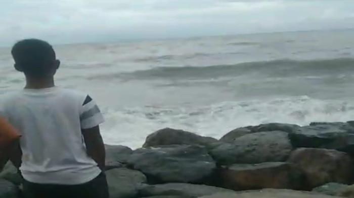 ORANG HANYUT: Sejumlah warga berdiri di tepi laut saat berusaha melihat seorang remaja yang dikabarkan hanyut saat berenang di Pantai Padang, Minggu (19/10/2025). Tim gabungan diturunkan untuk membantu mencari remaja yang dilaporkan hanyut tersebut.