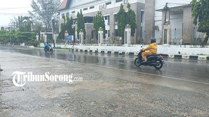 PAKAI JAS HUJAN - Pengendara sepeda motor melengkapi diri memakai jas hujan melintas di Jalan Pramuka, Remu, Kota Sorong, Papua Barat Daya, Sabtu (17/5/2025).