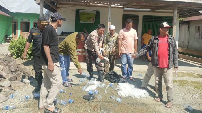 HUKUM: Personel Polsek Bacan Timur dan Pemdes Sayoang, Halmahera Selatan, Maluku Utara, saat memusnahkan ratusan kantong plastik berisi Miras jenis Captikus, Selasa (14/10/2025).