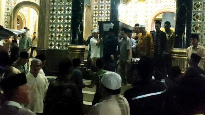 PENGHORMATAN TERAKHIR - Warga bahu membahu untuk menurunkan peti jenazah Moh Royhan Mustofa (17) menuju mobil ambulan menuju komplek pemakaman umum setelah dishalatkan di Masjid Syaikhona Yahya di Kampung Karang Anyar, Desa Banyuajuh, Kecamatan Kamal, Senin (6/10/2025) sekitar pukul 23.00 WIB.