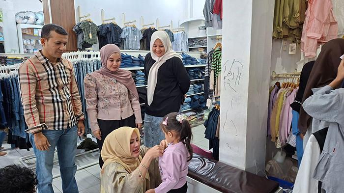 BELANJA BAJU DUAFA - Ketua TP PKK Pidie, Hj Rohana Razali STp memakaikan baju pada seorang anak saat belanja bareng sahabat duafa di Sigli, Pidie, Minggu (15/3/2026).