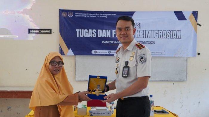 Kepala Kantor Imigrasi Kelas II TPI Sabang, Muchsin Miralza menyerahkan cendera mata kepada Wakil Kepala Sekolah SMAN 2 Sabang, Susi, usai acara sosialisasi Bahaya TPPO, Rabu (29/4/2026).