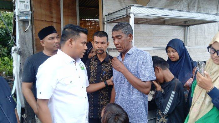 SERAHKAN BANTUAN - Anggota DPRA dari Fraksi PKB, Munawar AR (Ngohwan) menyerahkan bantuan kepada Amri di depan gubuk tempat ia tinggal di Gampong Lamteh, Kecamatan Peukan Bada, Aceh Besar, Kamis (13/11/2025).