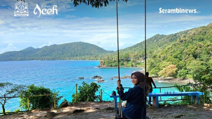 GUA SARANG - Wisatawan duduk di ayunan sambil menikmati panorama laut biru dan perbukitan hijau di kawasan wisata Gua Sarang, Desa Iboih, Sabang, 30 Oktober 2025.