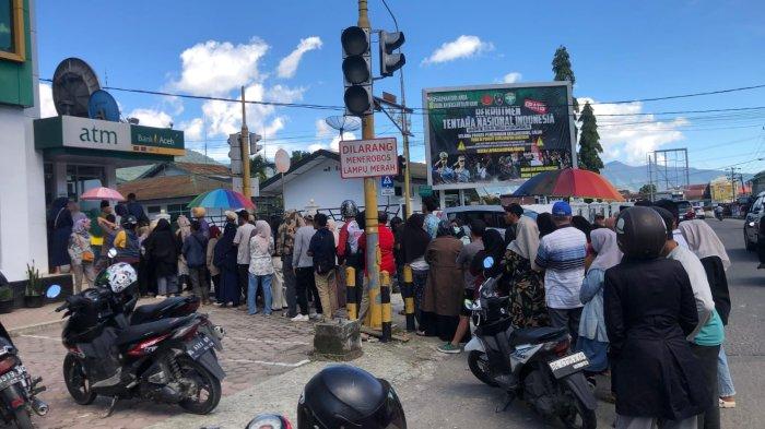Warga mengantre mengambil uang di ATM Bank Aceh dekat Kodim Aceh Tengah, Takengon, Minggu (30/11/2025).