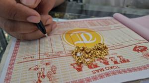 Emas-perhiasan-bentuk-kalung-di-toko-Tiara-dan-pekerja-sedang-menulis-surat-bukti-pembelian-emas.jpg