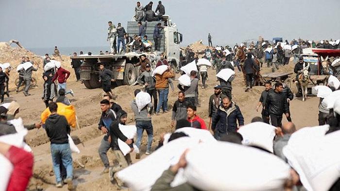 Sejumlah-warga-Palestina-membawa-sekarung-tepung-yang-diambil-dari-truk-bantuan-di-dekat-pos.jpg