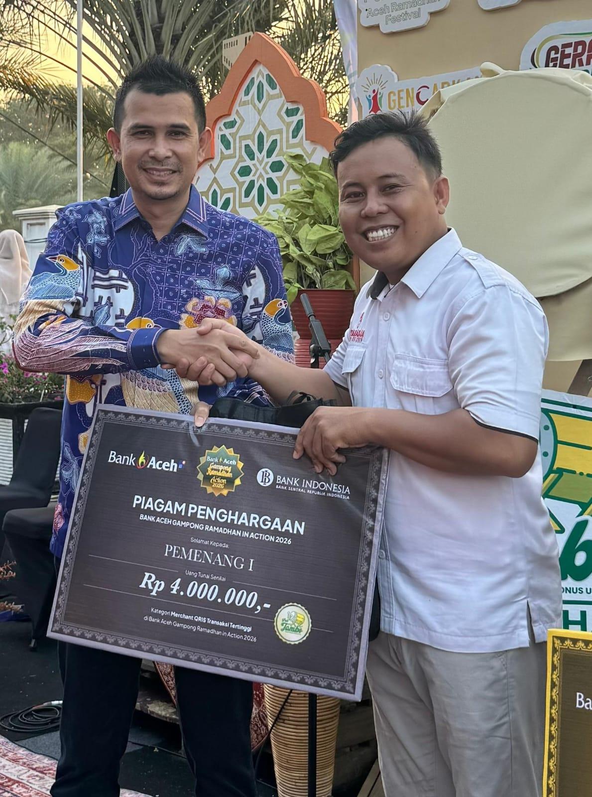 Direktur Dana dan Jasa Bank Aceh, M Hendra Supardi (kiri), menyerahkan piagam penghargaan kepada perwakilan Kutaradja Fried Chicken sebagai juara pertama Merchant QRIS dengan transaksi tertinggi pada Gampong Ramadhan in Action 2026 di kawasan Masjid Raya Baiturrahman, Sabtu (7/3/2026).