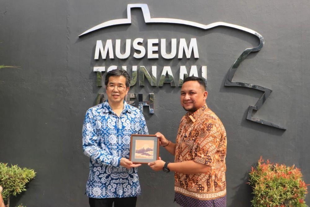 MENYERAHKAN CENDERA MATA – Kepala UPTD Museum Tsunami Aceh, M. Syahputra AZ, menyerahkan cendera mata kepada Kosulat Jenderal Jepang di Medan, Furugori Toru, saat berkunjung ke Museum Tsunami Aceh, Kamis (14/8/2025).