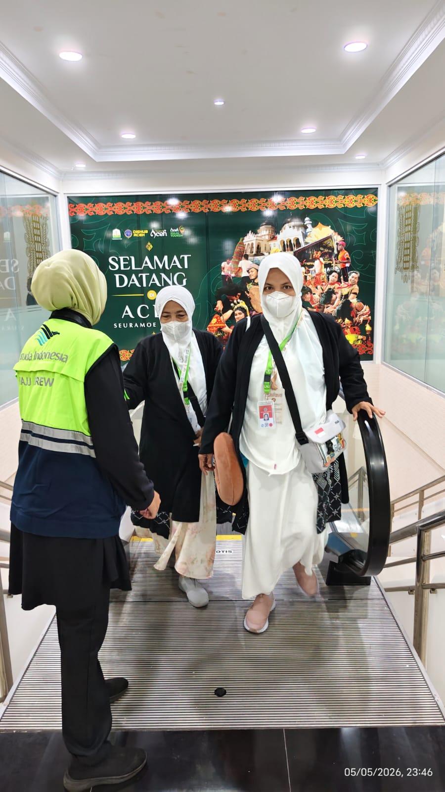 Petugas Bandara Sultan Iskandar Muda membantu jemaah haji kloter pertama saat turun dari bus menuju area keberangkatan, Rabu (6/5/2026) dini hari. Sebanyak 393 jemaah asal Banda Aceh dan Aceh Besar diberangkatkan menuju Tanah Suci menggunakan maskapai Garuda Indonesia.