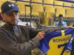 Seorang-penggemar-memegang-kaus-bertuliskan-nama-Ronaldo-di-toko-Saudi-Al-Nassr-FC.jpg