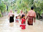 Warga-Aceh-Utara-berjalan-di-atas-jalan-desa-yang-terendam-banjir-Rabu-5102022.jpg