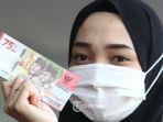 Warga-memperlihatkan-uang-pecahan-Rp-75000.jpg