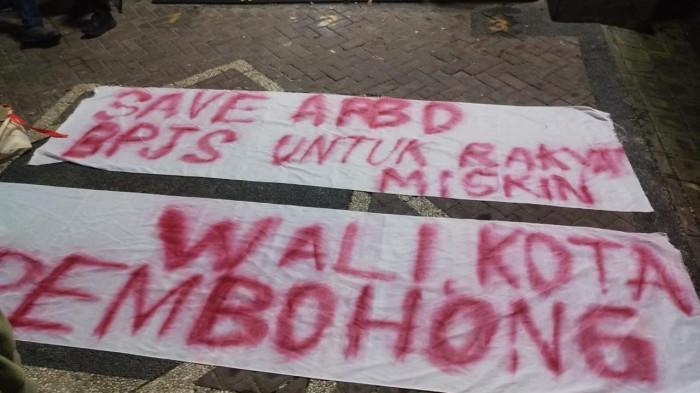 Spanduk yang dibentangkan di Kantor BPJS Kesehatan Denpasar, pada Sabtu 21 Februari 2026 malam. Polisi Selidiki Penyerangan Kantor BPJS Denpasar Bali: Pelaku Berkelompok Gunakan Masker