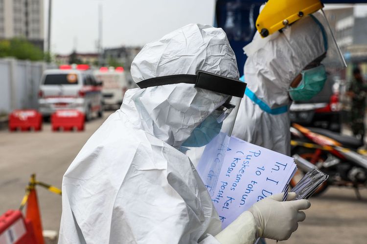 petugas-kesehatan-menggunakan-alat-pelindung-diri-saat-memberikan-berkas-pasien-covid-19.jpg