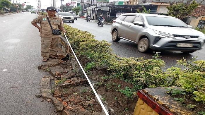 POT BUNGA RUSAK -- Petugas Dinas Lingkungan Hidup (DLH) Kota Pangkalpinang melakukan pengukuran median Jalan Jenderal Sudirman yang rusak pascademonstrasi di depan Kantor PT Timah Tbk, Selasa (7/10/2025). Sebanyak 10 titik median dan 17 pot besi bunga dilaporkan mengalami kerusakan akibat aksi tersebut.