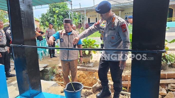 SUMUR BOR -- Dansat Brimob Polda Babel, Kombes Pol Ahmad Arif Sofiyan bersama warga saat melakukan uji cona menyalakan kran air di sumur bor, Selasa (11/11/2025).