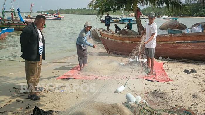 RAPIKAN JARING -- Beberapa orang nelayan merapikan jaring usai melaut di pesisir pantai Batu Perahu, Senin (5/1/2026). Di tengah cuaca barat laut yang cenderung ekstrem, aktivitas nelayan tetap berlangsung karena kondisi tersebut justru membawa peningkatan hasil tangkapan ikan, terutama ikan bawal hitam, meski harga jual ikan di pasaran sedang mengalami penurunan.