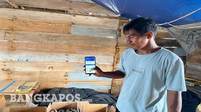 Arman (36), nelayan sekaligus pelaku usaha ikan asin di Desa Pongok, Kecamatan Kepulauan Pongok, Kabupaten Bangka Selatan, menunjukkan aplikasi BRImo di telepon genggamnya saat ditemui di tempat pengolahan ikan asin miliknya, Kamis (21/5/2026).