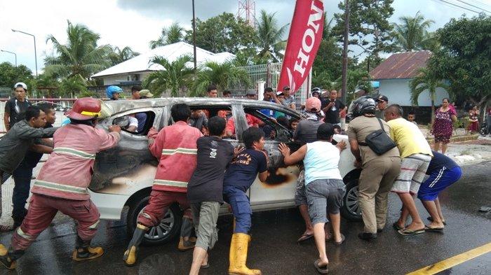 Petugas Damkar bersama warga dan babinsa mendorong mobil yang terbakar di depan SPBU Jalan Pilang, Desa Dukong, Jumat (24/1/2020) 