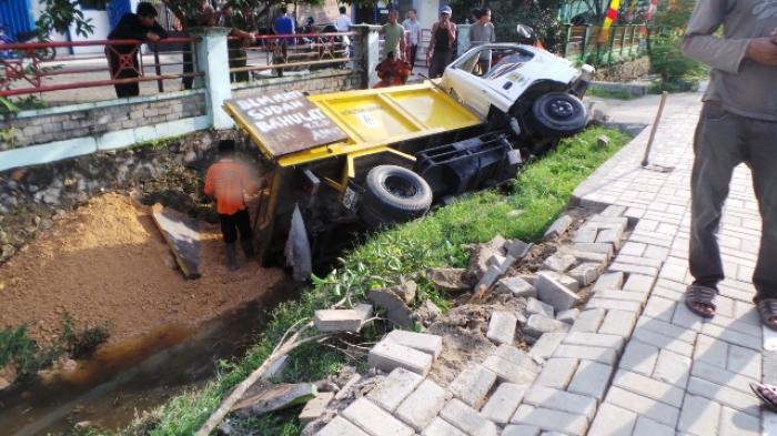 Truk Pengangkut Sampah Terguling Masuk ke Saluran Air