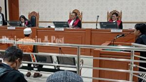 Saprudin-tampak-mengenakan-peci-putih-saat-duduk-di-hadapan-majelis-hakim2.jpg