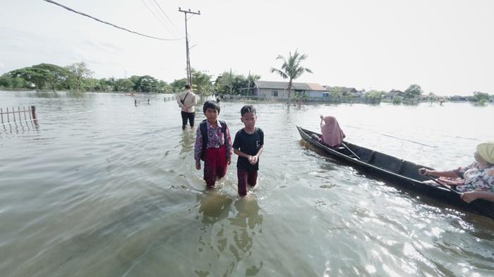 Sejumlah-anak-berjalan-menerobos-genangan-banjir-di-Desa-Sungai-Tabuk-Keramat.jpg