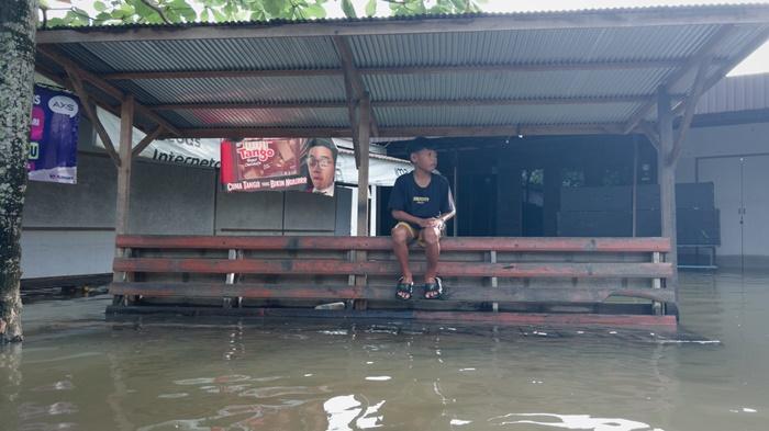 Seorang-anak-duduk-di-tengah-banjir-yang-melanda-Desa-Sungai-Tabuk-Keramat.jpg