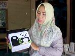 Hj-Hatimah-Rasyidah-dengan-karya-celengan-kardus-karya-perempuan-kreatif-di-komunitasnya.jpg