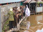 Kajati-Kalsel-dan-Ketua-IAD-Kalsel-beserta-jajaran-melewati-titian-kayu-menyerahkan-bantuan.jpg