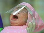 seorang-perawat-menggendong-bayi-yang-baru-lahir-yang-dilindungi-dengan-pelindung-wajah.jpg