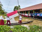 tiga-siswa-mengibarkan-bendera-dari-atas-perahu.jpg