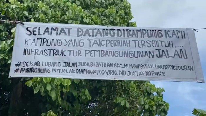 Warga Kampung Pasirguling, Desa Banjarsari, Kecamatan Warunggunung, Kabupaten Lebak, Banten, memasang spanduk protes di atas ruas jalan desa yang rusak parah, Minggu (9/11/2025).